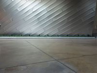 the front side of a large modern building with metallic siding and a light shining on it