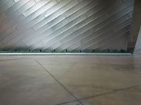 the front side of a large modern building with metallic siding and a light shining on it