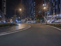 a roadway with empty lanes at night near tall buildings that are lighted up for advertising