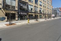 a lone street in front of a tall brick building with a store on it's side