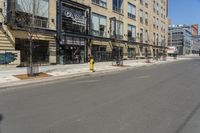 a lone street in front of a tall brick building with a store on it's side