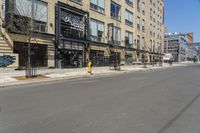 a lone street in front of a tall brick building with a store on it's side