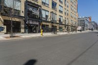 a lone street in front of a tall brick building with a store on it's side