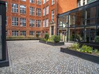 an empty parking lot with plants in the ground and on the side of the building, there is an enclosed area and windows