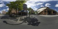 a city intersection with many buildings and trees around it in a 360 - ray lens