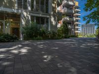 a paved brick street with red trash bins sitting in the middle and trees near to it