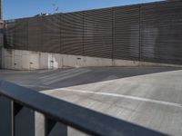 a skateboarder in the air above a railing in a parking lot with a fence