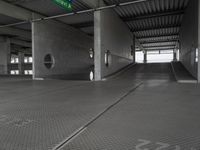 an empty building with a ramp in the middle of it and a green sign with directions