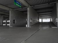 an empty building with a ramp in the middle of it and a green sign with directions