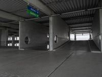 an empty building with a ramp in the middle of it and a green sign with directions