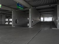 an empty building with a ramp in the middle of it and a green sign with directions