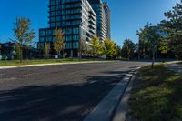 city streets with a building and many trees in front of it at daytime with blue sky