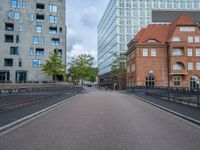 an empty street is shown with some buildings in the background while the pedestrian bridge leads down