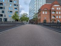 an empty street is shown with some buildings in the background while the pedestrian bridge leads down