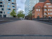 an empty street is shown with some buildings in the background while the pedestrian bridge leads down