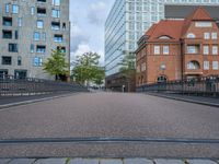 an empty street is shown with some buildings in the background while the pedestrian bridge leads down