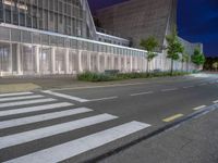 a crosswalk in the middle of an empty street with some buildings behind it at night