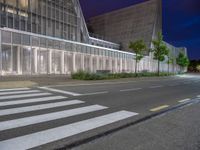 a crosswalk in the middle of an empty street with some buildings behind it at night