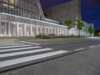 a crosswalk in the middle of an empty street with some buildings behind it at night