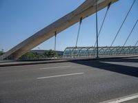 a truck driving across a bridge near a street corner near buildings and a bridge with many cables