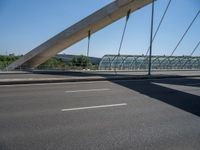 a truck driving across a bridge near a street corner near buildings and a bridge with many cables