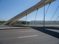 a truck driving across a bridge near a street corner near buildings and a bridge with many cables