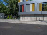 a fire hydrant sitting outside a colorful building next to a green tree line of trees