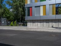 a fire hydrant sitting outside a colorful building next to a green tree line of trees