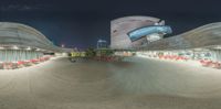 a fish eye view of some chairs on a patio at night in the foreground are two large buildings