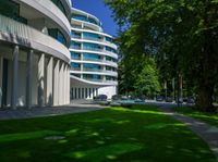 a house with large green lawn in front of it and a building with several balconies on the second floor