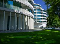 a house with large green lawn in front of it and a building with several balconies on the second floor