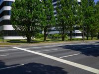 street view of city buildings and trees in front of the road, seen from across an empty street