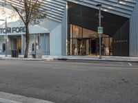 the entrance of a store that is located on the sidewalk in front of a tree