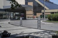 a person sitting at the bench in front of a mall that is empty of people