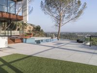 patio that overlooks the mountains and trees of a home with a swimming pool surrounded by grass