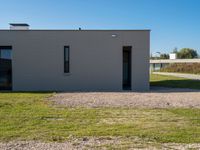 a cement house with small white doors on it's side, with grass and a paved walkway and a dirt path in front of it