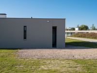 a cement house with small white doors on it's side, with grass and a paved walkway and a dirt path in front of it