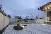 a modern style yard with grass and stepping stones under the roof and steps leading up to a large stone monument