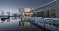 three rows of white chairs sit along the edge of an outdoor pool at dusk with lights reflected in the water