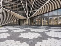 a walkway that has white geometric tiles on it in front of buildings with glass walls