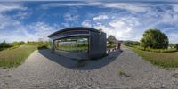 a fish eye view of a walkway leading through a grass field with a train parked on the side