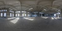 a fisheye lens reflecting a building inside and outside with people standing inside, one person on the ground, while the other is sitting