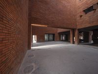 an empty building with concrete floor next to red brick wall and sidewalk area in front