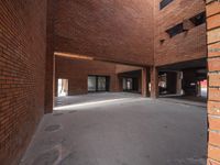 an empty building with concrete floor next to red brick wall and sidewalk area in front