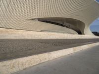 an outdoor walkway with steps that are made of stone and cement, leading to a white building