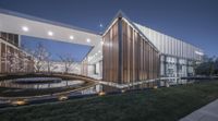 the building is wooden and glass on top of it, and the walkway outside is illuminated by low lights