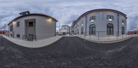 a 360 lens image of two buildings on a city street with a ramp, and another half empty street