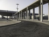 a deserted street under a large walkway on top of an airport building to enter a terminal