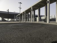 a deserted street under a large walkway on top of an airport building to enter a terminal