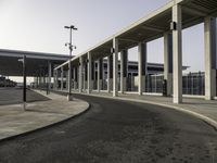 a deserted street under a large walkway on top of an airport building to enter a terminal